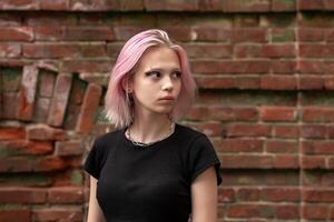 portrait de une adolescent fille avec rose cheveux sur une brique mur Contexte photo