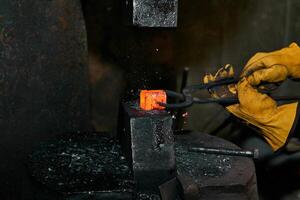 mains de ouvrier métallurgiste processus une rouge chaud pièce avec une Puissance marteau photo