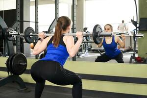 Jeune femme effectue le exercice s'accroupir avec haltère photo