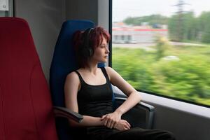 fille monte sur une banlieusard train et regards en dehors le fenêtre à un à l'extérieur paysage flou dans mouvement photo