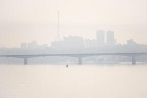 route pont plus de une large rivière et le silhouette de une loin ville derrière il dans le Matin brouillard photo