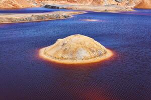 rond sablonneux île dans le milieu de une violet Lac dans vieux kaolin carrière photo