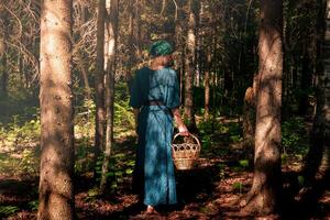 Jeune femme dans populaire paysan vêtements avec une osier panier des promenades dans le foncé forêt photo