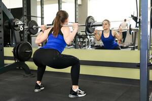 Jeune femme effectue le exercice s'accroupir avec haltère photo