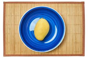 Jaune mangue sur une bleu assiette sur une canne portion tapis photo