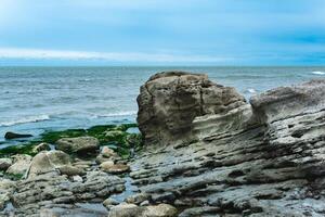 côte de le Caspienne mer avec côtier rochers et des pierres couvert avec algues photo
