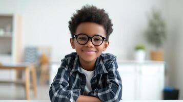 ai généré mignonne peu école garçon dans noir Cadre lunettes, garçon enfant séance à une bureau dans une blanc intérieur photo