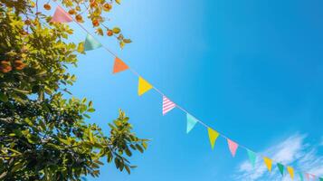 ai généré coloré fanion chaîne décoration dans vert arbre feuillage sur bleu ciel, été fête Contexte modèle bannière avec copie espace photo