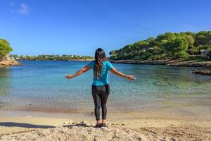 latina femme, dans tenue de sport sur sa dos, sur le rive de le plage à la recherche à le mer respiration profondément. photo