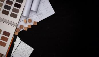 le architecte conçu le bâtiment dans le conception bureau, le sol plan avec catalogues décoratif matériaux et autre accessoires sur le noir en bois tableau. photo