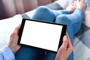 femme en portant numérique tablette avec Vide blanc bureau écran séance sur le lit. tablette Vide écran maquette. fermer. copie espace. photo