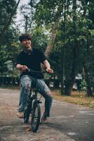 Jeune Beau barbu homme prise une Pause tandis que en voyageant le ville avec le sien vélo en utilisant le sien numérique tablette à la recherche une façon pensivement photo