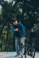 Jeune Beau barbu homme prise une Pause tandis que en voyageant le ville avec le sien vélo en utilisant le sien numérique tablette à la recherche une façon pensivement photo