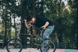 Jeune Beau barbu homme prise une Pause tandis que en voyageant le ville avec le sien vélo en utilisant le sien numérique tablette à la recherche une façon pensivement photo