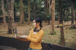 content Jeune asiatique femme tandis que équitation une vélo dans une ville parc. elle sourit en utilisant le vélo de transport. écologiquement amical concept. photo