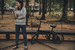 content asiatique Jeune femme marcher et balade vélo dans parc, rue ville sa souriant en utilisant bicyclette de transport, éco amical, gens mode de vie concept. photo