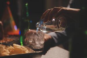 fête nuit, verser whisky dans une verre. donner à copains qui viens à célébrer photo