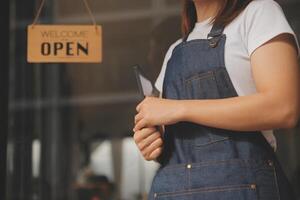 startup réussie propriétaire de petite entreprise PME beauté fille stand avec tablette smartphone dans un café-restaurant. portrait d'une femme asiatique bronzée propriétaire d'un café barista. PME entrepreneur vendeur concept d'entreprise photo