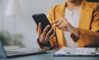 femme d'affaires asiatique en costume formel au bureau heureuse et joyeuse lors de l'utilisation d'un smartphone et du travail photo