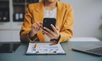 femme d'affaires asiatique en costume formel au bureau heureuse et joyeuse lors de l'utilisation d'un smartphone et du travail photo