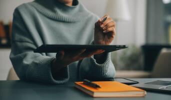 Jeune attrayant femelle directeur travail sur numérique tablette tandis que permanent dans moderne bureau. sur de soi affaires expert. attrayant Jeune souriant femme dans intelligent décontractée porter en portant numérique tablette photo