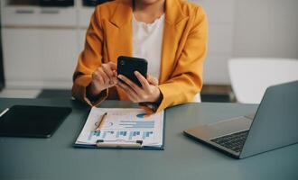 femme d'affaires asiatique en costume formel au bureau heureuse et joyeuse lors de l'utilisation d'un smartphone et du travail photo