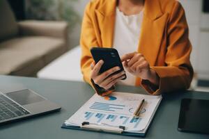 femme d'affaires asiatique en costume formel au bureau heureuse et joyeuse lors de l'utilisation d'un smartphone et du travail photo