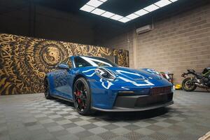 bleu porsche 911 gt3 avec artistique mural toile de fond dans moderne garage photo