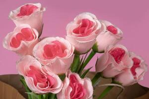 magnifique bouquet de rose des roses dans papier sac sur rose arrière-plan, fermer photo