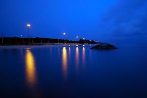 le route suit le côte à crépuscule et est allumé par lumière poteaux photo