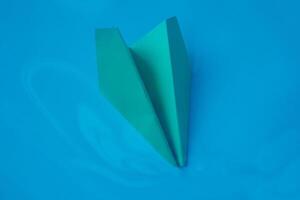 Jaune origami avion sur une bleu Contexte. photo