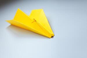 Jaune origami avion sur une blanc Contexte. photo