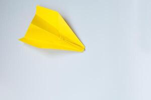 Jaune origami avion sur une blanc Contexte. photo