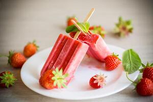 fait maison fraise la glace crème sur une bâton fabriqué de Frais des fraises dans une assiette photo