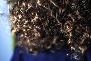 Naturel frisé cheveux, peu fille avec lumière marron boucles et d'or reflets photo