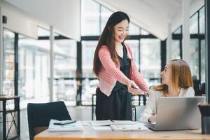 affaires équipe analytique concept, joyeux asiatique femme d'affaires partage les documents et des idées à une collaboratif Bureau espace de travail avec une portable. photo