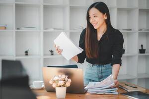 une contenu Jeune professionnel femme tri papiers dans une brillant Bureau environnement, démontrant organisation et flux de travail efficacité. photo