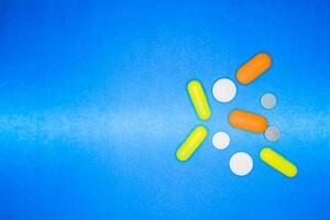 déversé coloré médicaments et pilules sur une bleu Contexte. pharmacologie et médicament lutte pour santé. drogue dépendance. traitement de divers maladies photo