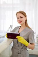 content femelle cosmétologue en portant boîte avec mains. portrait jolie femme portant Jaune gants et uniforme, montrant petit boîte. beauté, cosmétologie concept. photo