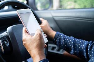 tenant un téléphone portable dans la voiture pour communiquer avec la famille et les amis. photo