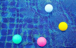 Haut vue de Plastique des balles flottant sur le surface de le eau, rebondir en haut et vers le bas de le l'eau vagues, création magnifique bleu et blanc motifs. photo