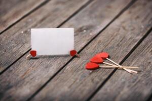 Trois rouge cœurs forme sur bâton avec papier carte plus de en bois Contexte. Valentin concept. sélectif se concentrer. fond pour texte. photo