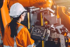 ingénieur équipe un service robot soudage travail dans automatisation usine. femme ouvrier fonctionner robotique bras Logiciel main manette dans automatique fabrication industrie technologie. photo