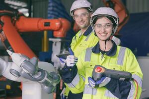 content ingénieur équipe portrait les pouces en haut prendre plaisir travail ensemble dans moderne métal usine avec robotique bras photo