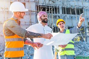 ingénieur équipe groupe avec arabe affaires biens projet directeur vérifier sol plan de bâtiment à construction site photo