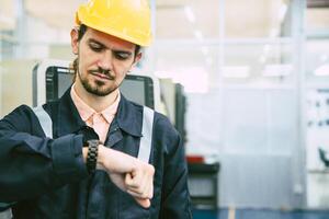 ingénieur ouvrier à la recherche à montre-bracelet. industrie usine travail heures après midi Pause fois pour le déjeuner photo