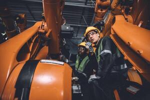 ingénieur équipe un service réparer robot soudage bras travail dans automatisation usine. gens ouvrier travail dans robotique bras Assemblée plante lourd métal industrie. photo