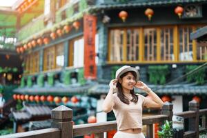 femme voyageur visite dans Taïwan, touristique avec chapeau tourisme dans Jiufen vieux rue village avec thé maison Contexte. point de repère et populaire attractions près Taipei ville . Voyage et vacances concept photo