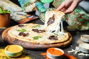 la personne doucement enlever une tranche de Pizza de une graissé Pizza la poêle photo