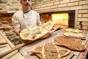 homme en portant Pizza dans de face de brique four photo